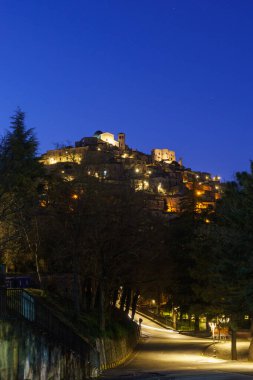 Morano Calabro 'nun alacakaranlıkta sarı sokak ışıklarıyla mavi saat boyunca gece görüşü. Cosenza ili, Calabria, İtalya