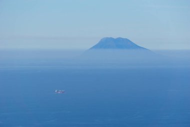 Mavi deniz ve gökyüzü ile uzak Stromboli volkanı. Puslu güneşli bir günde Palmi, Calabria, İtalya 'dan görüldü.