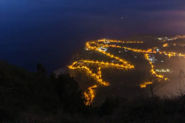 Akdeniz 'in aydınlık yılanlı sahil caddesindeki hava manzarası gece alacakaranlığı sırasında Palmi, Calabria, İtalya