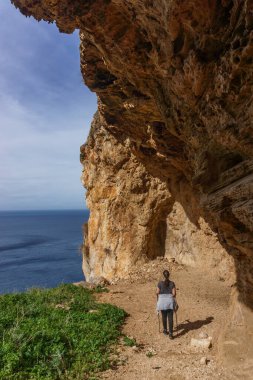 Akdeniz, San Vito Lo Capo, Sicilya, İtalya 'daki Monte Cofano Doğa Parkı' nın kayalık kıyı şeridinde mağarada duran yürüyüşçü.