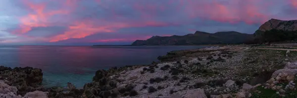 Akşam alacakaranlığında Nature Park Monte Cofano 'da turkuaz suyla kıyı şeridinin panoramiası kırmızı ışıklı gökyüzü, San Vito Lo Capo, Sicilya, İtalya