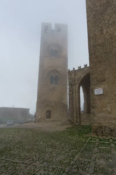 Stock image Medieval bell tower of King Federicoat in misty clouds with Real Duomo di Erice on a foggy day, Erice, Sicily, Italy