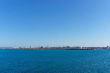 Güneşli bir günde, Brindisi, Puglia, İtalya 'nın Brindisi limanı yakınlarındaki sanayi bölgesi olan Pedagne' ye mavi deniz suyunun üzerinden bakın.