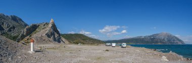 Panorama of camper vans on road trip in front of rocky landscape at Limnopoulas Beach on the mediterranean sea, Kato Vasiliki, Western Greece, Greece clipart