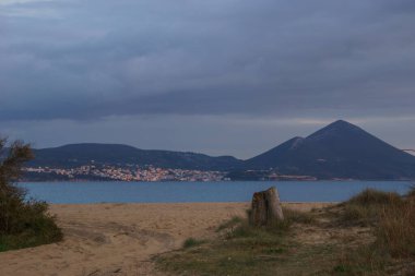 Bulutlu bir bahar akşamında Navarino Körfezi 'ndeki plajdan dağ manzarasına Messinia, Moreloponnese, Yunanistan