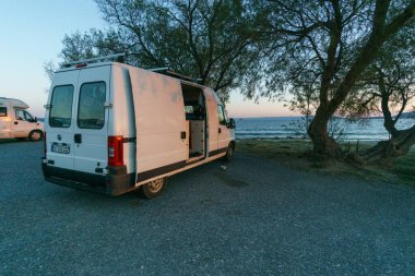 Gün batımında denize bakan bir ağacın altında duran karavan, Laconia, Moreloponnese, Yunanistan