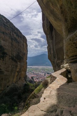 Meteora 'nın ünlü kaya oluşumlarında kutsal üçleme manastırına doğru yürüyüş yolu ve vadideki şehir Kalambaka, Thessaly, Yunanistan manzarası