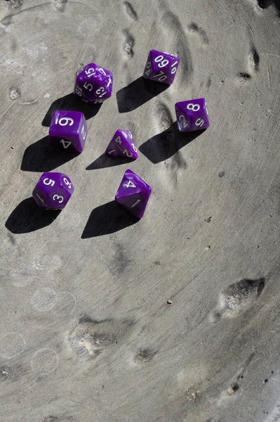 Top down view of purple role playing game dice on stone ruins.