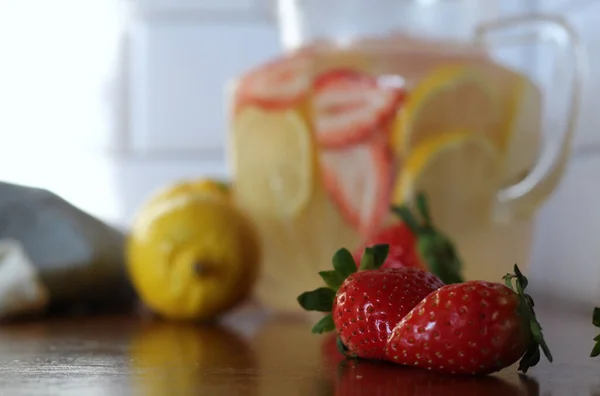 Close up of two strawberries with strawberry lemonade blurred in the background.