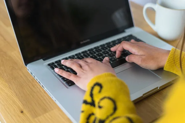 Laptopuyla çalışan bir kadın, yanında bir kupa çayla ve tahta bir masanın üstünde siyah ekranla. Yüksek kalite fotoğraf