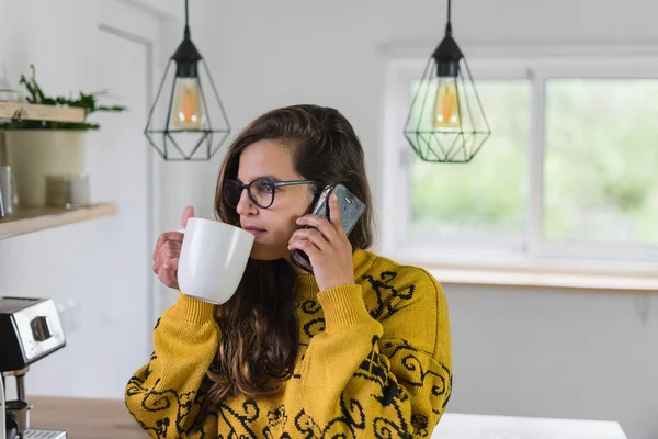 stock image Woman drinking a hot drink from a white cup while doing business on her cell phone. High quality photo