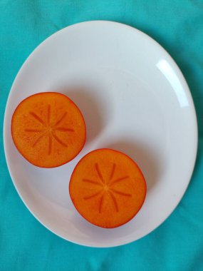 Taze kırmızı hurma bir tabakta meyve dilimler.