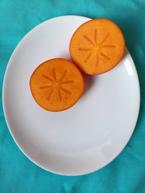 Taze portakal hurması beyaz tabakta.