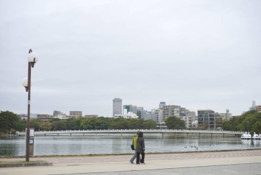Fukuoka, Japonya - 4 Aralık 2022: Ohori Park 'ın nehir kenarı atmosferi, köprü ve şehir arka planda