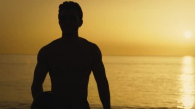 Silhouette of a man at sunset with American football ball.