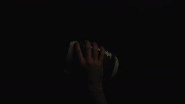 Hand Holding A Football ball on black background 