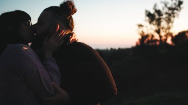Close up of young engaged couple kissing at sunse.