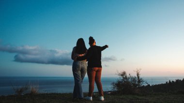 engaged couple looks towards the horizon.