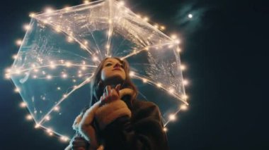 Happy girl with transparent umbrella with fairy lights