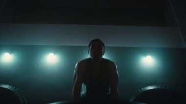 Crossfit spor salonunda lastik çeviren güçlü bir adamın ön görüntüsü.. 