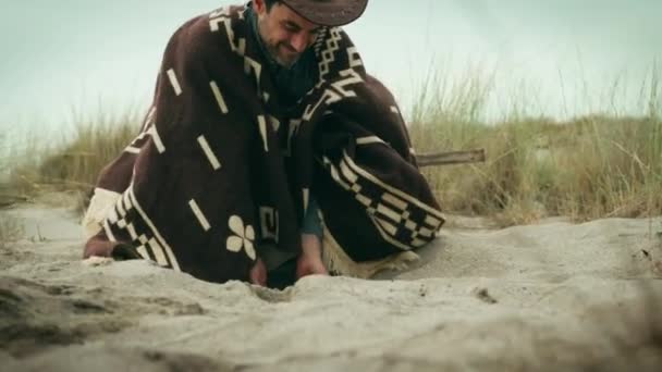 Чоловік Пончо Копає Руками Піску — стокове відео