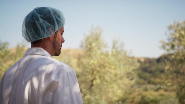 身穿实验室外套的科学家凝视着乡间的橄榄树 — 图库视频影像