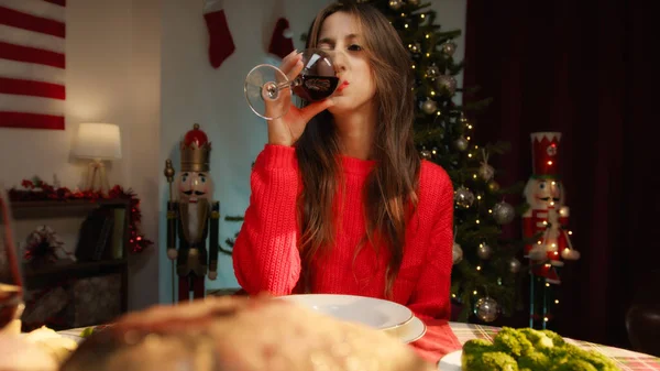 Girl drinking wine and cheering with the table set for thanksgiving.