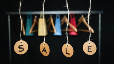 Arka planda alışveriş torbaları ve koltuk değnekleriyle etiketler..
