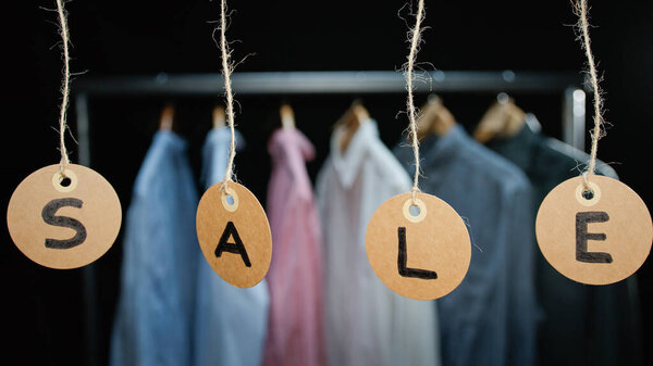 Sale tags with clothes in the background.