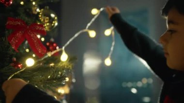 Çocuk Noel ağacına ışık tutuyor. . 