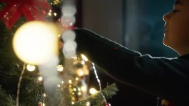 Noel ağacını ışıklarla süsleyen çocuk . 