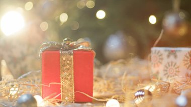 Altın kaplama arkaplanlı kırmızı Noel hediyesi.