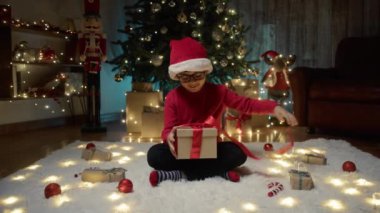 Çocuk ağacın altında Noel hediyesini açıyor. . 