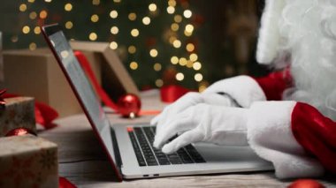 Noel Baba bilgisayarda yazı yazıyor ve akıllı telefonu kaydırıyor . 