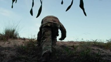 Alone soldier comes out of dense vegetation.