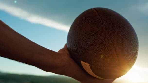 Hand Hält American Football Ball Bei Sonnenuntergang — Stockvideo