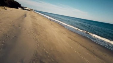 Sahilde koşan bir adamı takip eden dalgalar . 