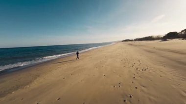 Kumsalda koşan yorgun bir adamın üzerine gün batımı ışığı.. 