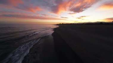 Güneşin doğduğu bir sahilin deniz manzarası . 
