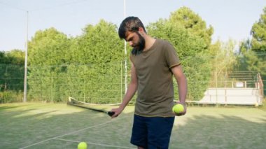 Tenis topuna raketle top süren adam. . 