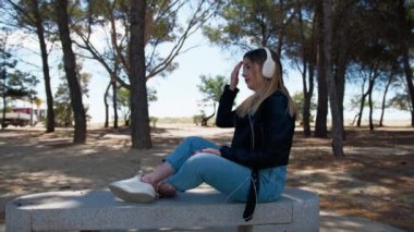 Kadın bankta müzik dinliyor. . 