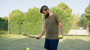 Tenis topuna raketle top süren adam. . 