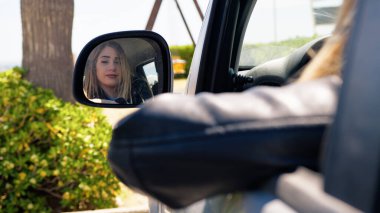 Arabanın aynasında kendini yansıtan kadın. . 