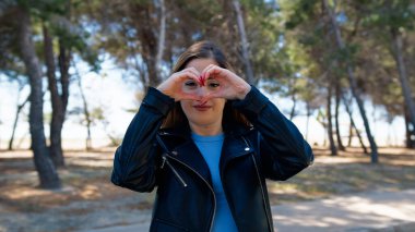 Elleriyle kalp şeklini alan bir kadın. . 