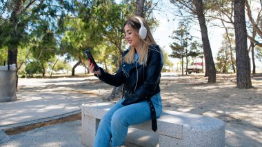 Telefonundan müzik dinleyen bir kadın. . 