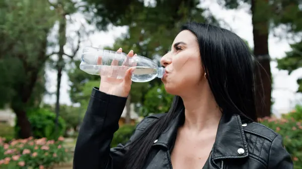 Parktaki su şişesinden içen kadın. .