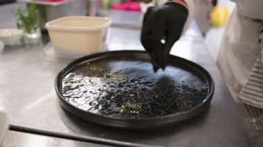 Şef siyah tabağın üzerindeki yemeği sunmaya hazır. .