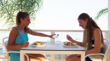 Kadınlar sahilde güzel yemeklerin tadını çıkarıyorlar. 