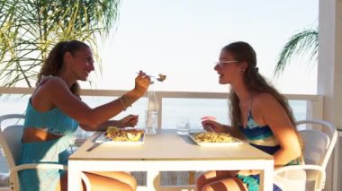 Kadınlar sahilde güzel yemeklerin tadını çıkarıyorlar. 