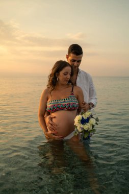 Bir çift gün batımında bebek paylaşımı bekliyor..